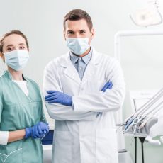 dentists in masks standing with crossed arms in dental clinic