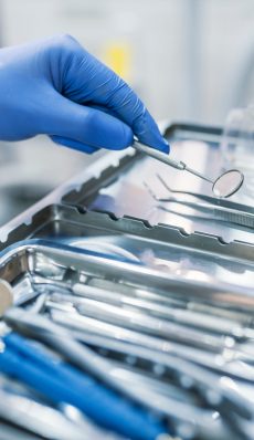Dental tool and other accesries used by dentists in the office. Detail of hand holding dental tools in dental clinic. Dentist Concept. Dentists with a patient during a dental intervention.